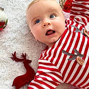 James a rejoint le concours — aidez-le/la à gagner de superbes lots ! baby, infant, red_striped_clothing, christmas_ornaments, plush_reindeer, white_blanket, holiday, festive, blue_eyes, cute, portrait, smiling, child, soft_texture, cozy, seasonal, celebration, decoration, holiday_outfit, lying_down