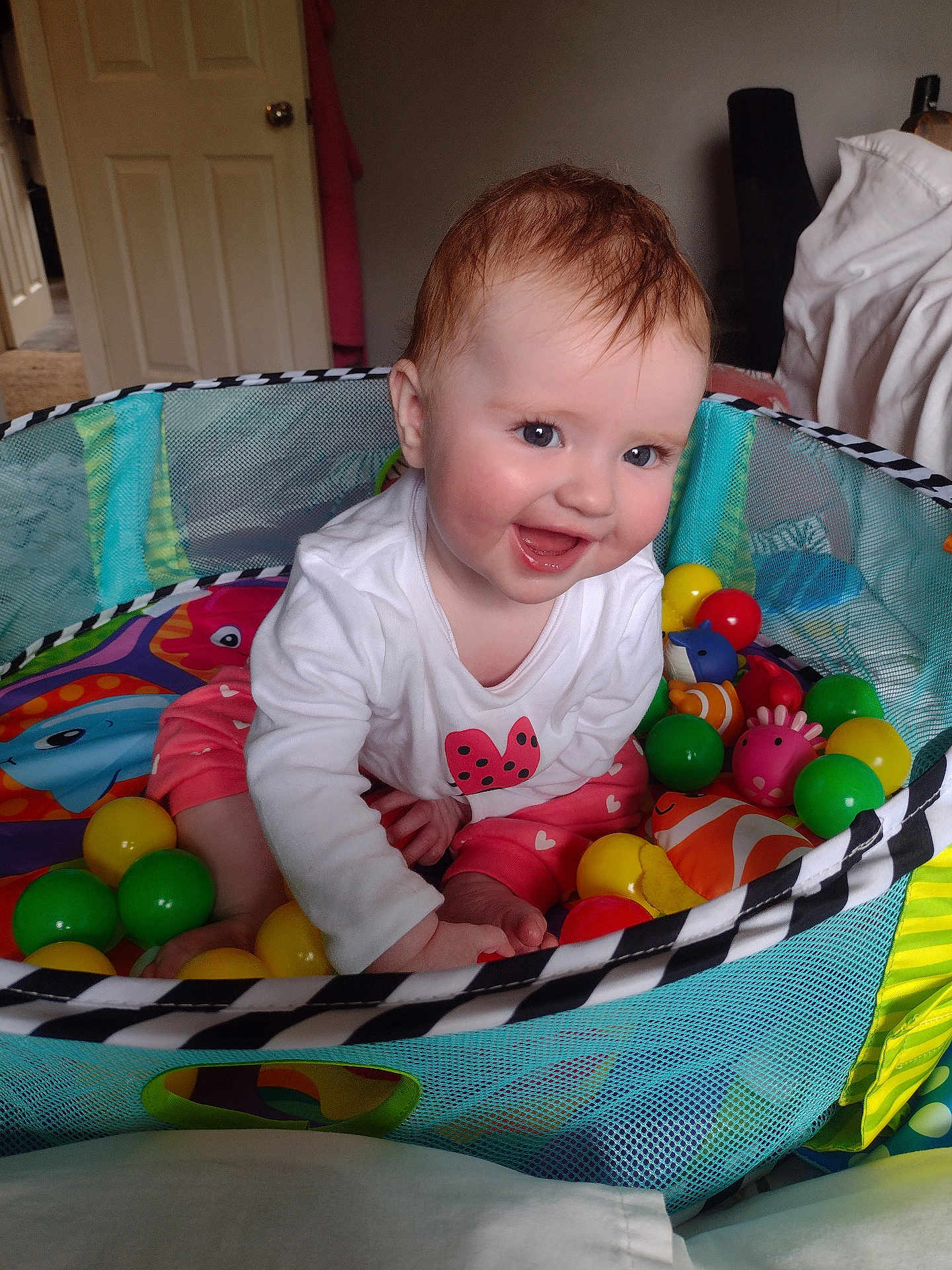 Freya joined the competition — help win amazing prizes! baby, child, playpen, toys, balls, smiling, happy, indoors, colorful, clothing, sitting, face, person, cute, infant, playtime, mesh, home, cheerful, young