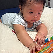 Ezekiel joined the competition — help win amazing prizes! baby, infant, child, portrait, bed, bedding, indoors, bedroom, lying_down, reaching, toy, activity_book, colorful, striped_clothing, short_sleeves, dark_hair, curious, face, hands, cozy