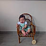 baby, child, smiling, green_overall, white_shirt, wooden_chair, indoor, floor, window, wall, plaque, milestone, happy, cute, portrait, toes, sitting, person, home, young