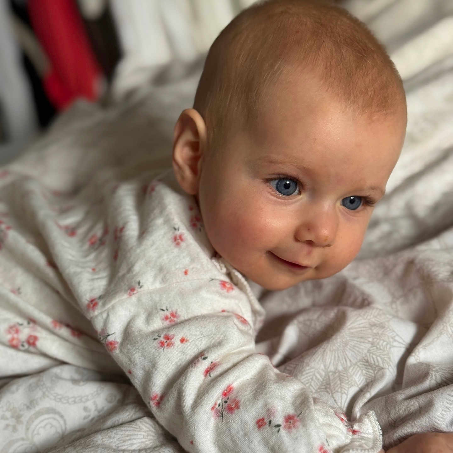 Joy participe au concours pour gagner de l'argent avec cette photo : baby, blue_eyes, blanket, child, clothing, cute, face, floral_pattern, infant, laying_down, looking_away, person, portrait, sleepwear, soft_fabric, smiling, toddler, white, young_child, indoors