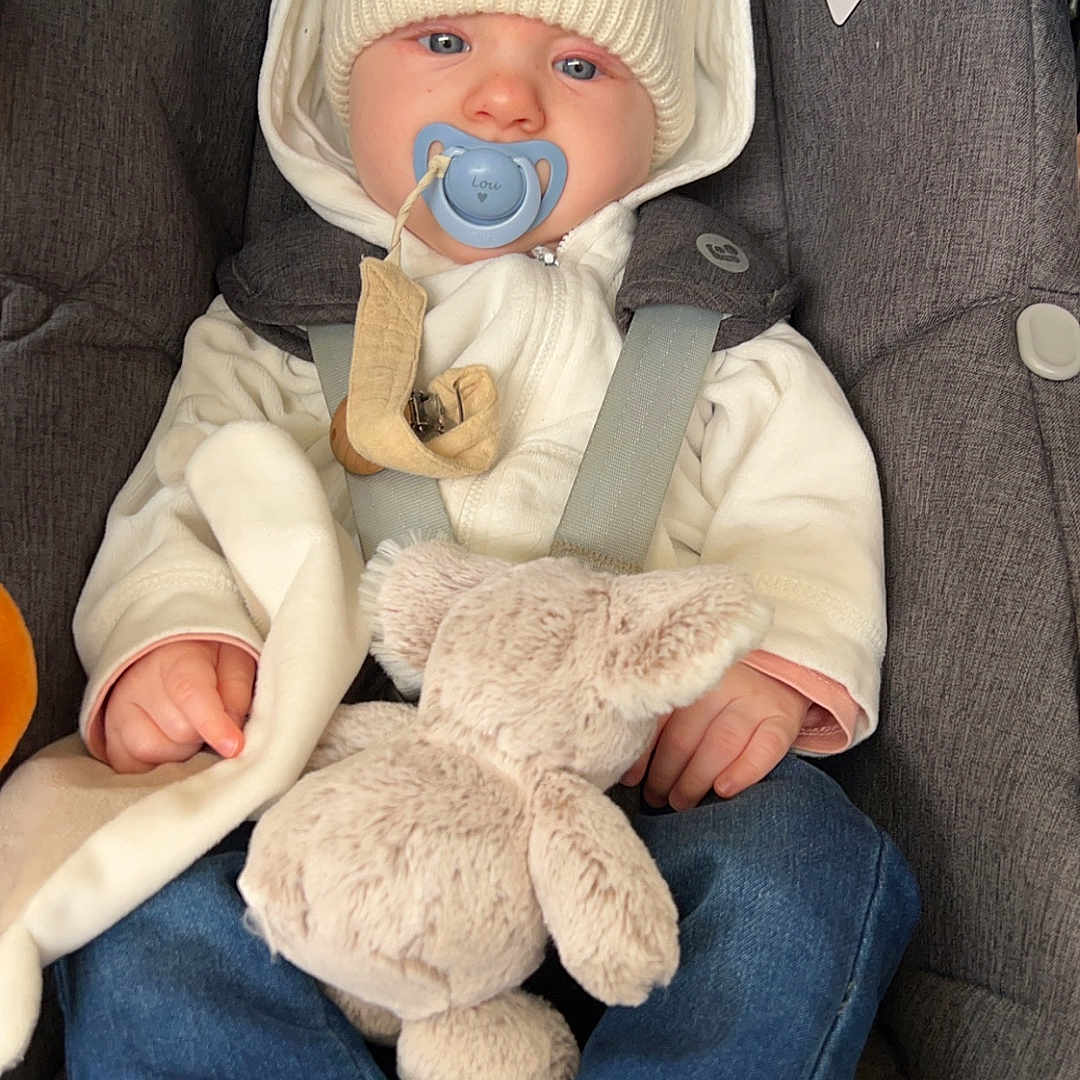 Lou a rejoint le concours — aidez-le/la à gagner de superbes lots ! baby, beanie, bonnet, cap, car, car_interior, clothing, couch, face, furniture, hat, head, jeans, newborn, pants, person, photography, portrait, transportation, vehicle