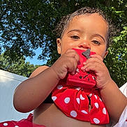 Kazora is registered to the contest to win money with this photo: child, toddler, red_clothing, polka_dot, toy, outdoor, sunlight, trees, greenery, blue_sky, cute, face, hands, summer, playful, baby, nature, happy, skin, dress