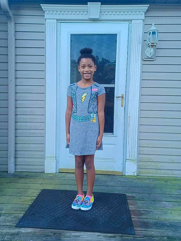 Olivia is registered to the contest to win money with this photo: blue, child, denim, door, electric_blue, flooring, fun, grass, house, human_leg, joy, leisure, magenta, person, recreation, siding, standing, symmetry, t_shirt, toddler