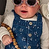 accessory, baby, blanket, blue, child, clothing, comfort, cute, denim_overall, face, floral_pattern, glasses, hand, indoors, infant, lying_down, smiling, sunglasses, toy, wooden_beads