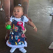 Alani joined the competition — help win amazing prizes! toddler, child, denim_dress, ball, tattoo, bracelet, birthday_ribbon, white_shoes, indoor, concrete_floor, adult_hands, cute, colorful_clothing, standing, helping_hand, hair_bow, playful, person, celebration, casual