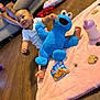 Alani joined the competition — help win amazing prizes! baby, baby_bottle, child, cookie, cookie_monster_toy, couch, feet, floor, happy, home, indoor, person, pink_blanket, playtime, plush_toy, relaxed, smiling, snack, toy, wooden_floor