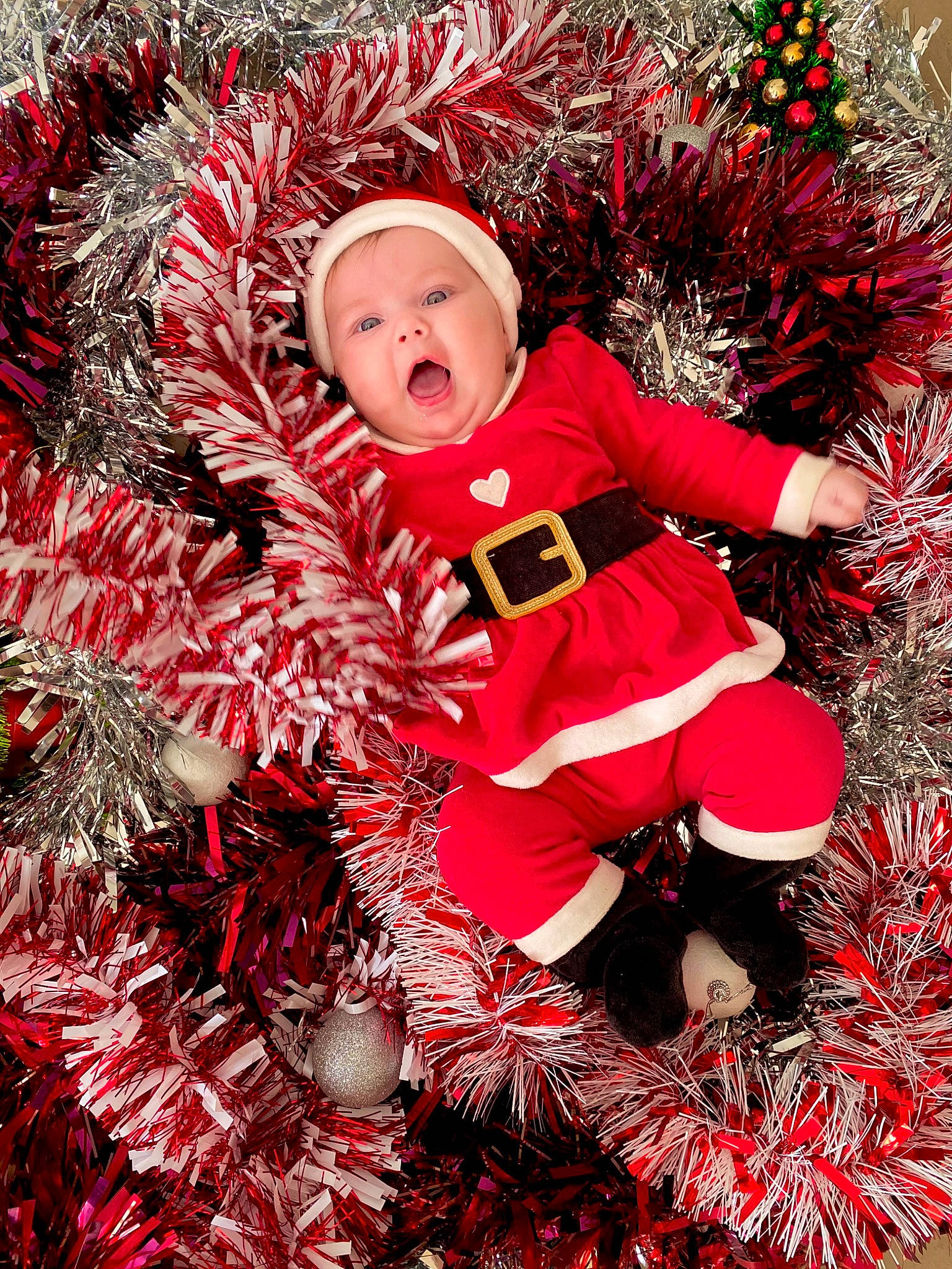 Raven participe au concours pour gagner de l'argent avec cette photo : baby, baby_toddler_clothing, carmine, christmas, christmas_decoration, christmas_eve, christmas_ornament, christmas_tree, costume_hat, event, fictional_character, grass, happy, hat, headwear, holiday, pattern, people_in_nature, person, pink