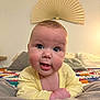 Sonny is registered to the contest to win money with this photo: baby, infant, yellow_clothing, face, eyes, mouth, expression, bed, pillow, blanket, quilt, decor, fan, indoor, cute, child, portrait, closeup, skin, person