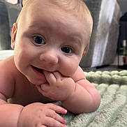 Noah joined the competition — help win amazing prizes! baby, infant, child, face, hand, fingers, blanket, texture, indoor, living_room, furniture, blurred_background, curious, cute, soft_lighting, skin, portrait, close_up, expression, smile