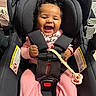 Miela joined the competition — help win amazing prizes! baby, infant, child, smiling, laughing, car_seat, harness, pink_clothing, curly_hair, pacifier, baby_toy, seated, portrait, indoor, vehicle, safety_belt, joyful, closeup, black_car_seat, photography