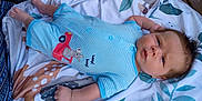 Everett joined the competition — help win amazing prizes! animal_pattern, baby, baby_girl_or_boy, blanket, blue_clothing, child, chubby_cheeks, curious_expression, cute, human, indoor, infant, lying_down, newborn, onesie, portrait, sleepwear, soft_lighting, striped_clothing, toddler