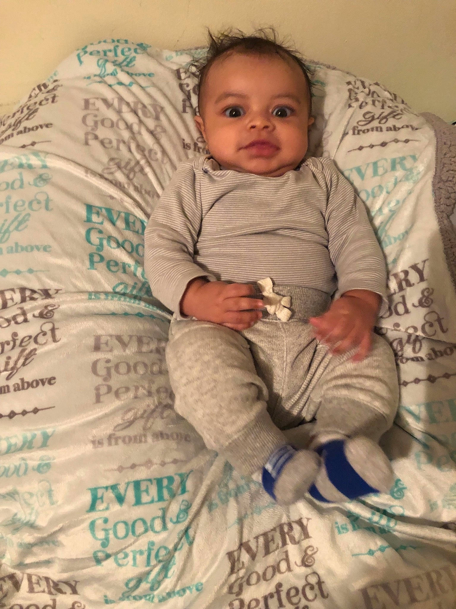 Jermaine is registered to the contest to win money with this photo: baby, bedding, bedtime, blanket, cheek, child, comfort, linens, person, sitting, smile, textile, toddler
