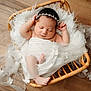 newborn, baby, sleeping, basket, white_fabric, pearls, flowers, headband, wooden_floor, cozy, wrapped, infant, peaceful, cute, resting, soft, decorative, tulle, portrait, indoors