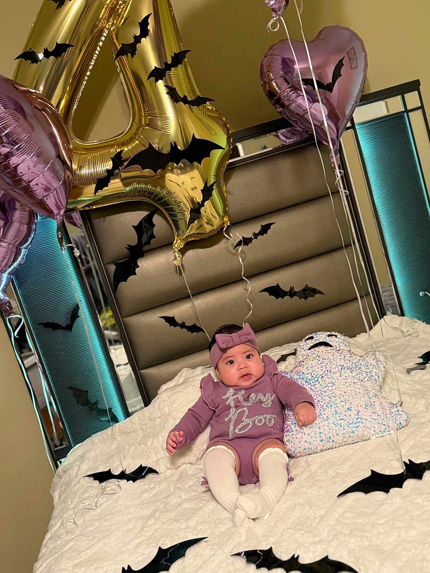 Daleyza is registered to the contest to win money with this photo: baby, infant, bed, balloon, number_balloon, heart_balloon, headband, purple_clothing, white_tights, ghost_pillow, black_bats, halloween_decorations, bedroom, mirror, blanket, festive, cute, holiday, indoor, child