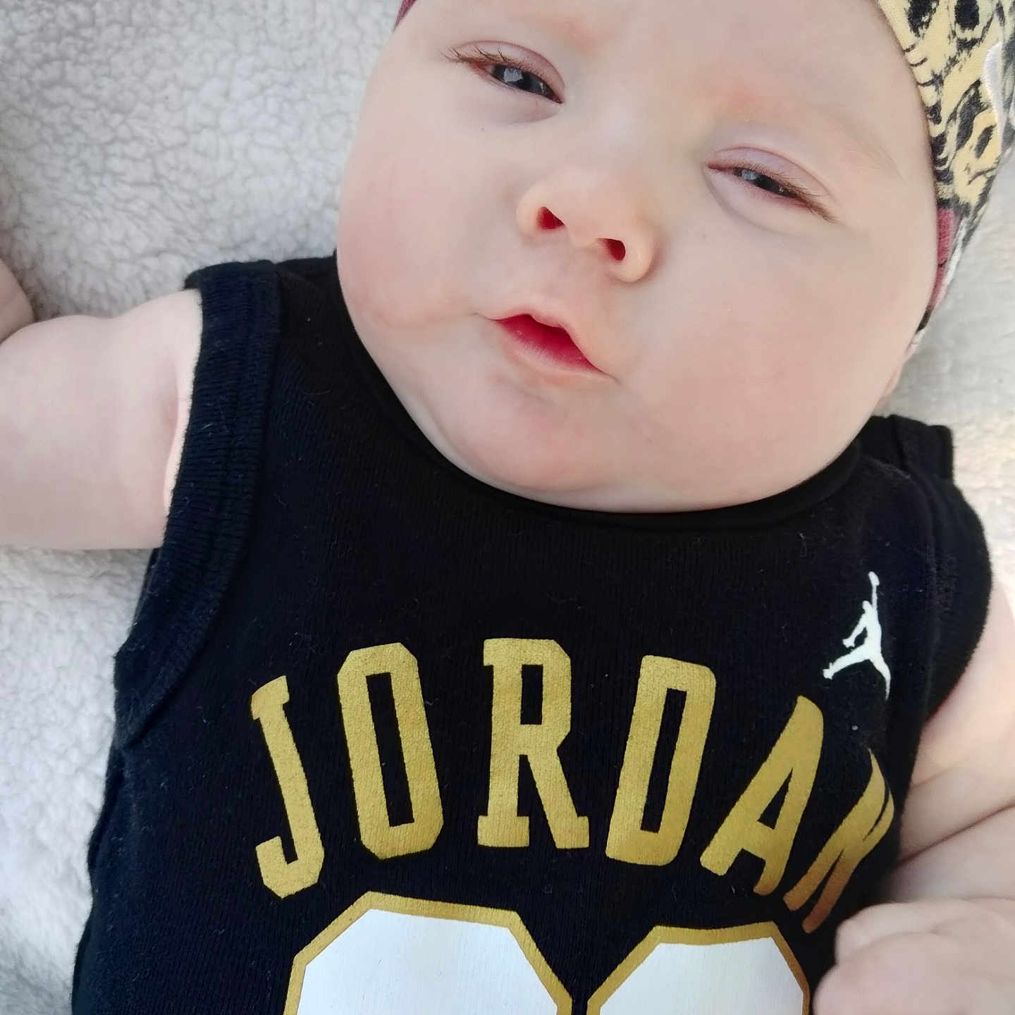 Rovie joined the competition — help win amazing prizes! baby, black_clothing, child, close_up, cute, expression, face, fashion, hand, headband, indoor, infant, jersey, lying_down, number_23, person, portrait, skin, soft_blanket, young