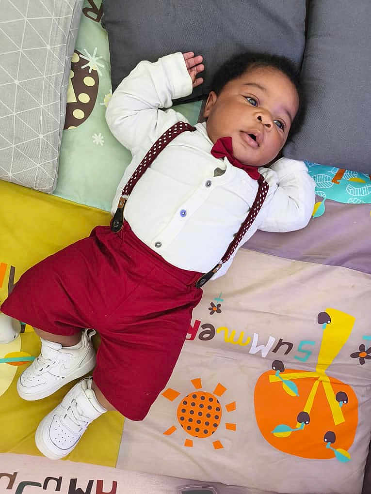 Jahyan participe au concours pour gagner de l'argent avec cette photo : adorable, baby, child, colorful, cute, footwear, head, indoors, infant, lying_down, maroon_shorts, maroon_suspender, patterned_mat, pillow, play_mat, portrait, relaxed, small_hands, sneakers, white_shirt