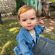 Céleste participe au concours pour gagner de l'argent avec cette photo : toddler, child, denim_jacket, outdoor, garden, grass, stone_wall, green_door, table, mesh_table, curious, portrait, daylight, nature, young_child, person, face, red_hair, expression, casual_clothing
