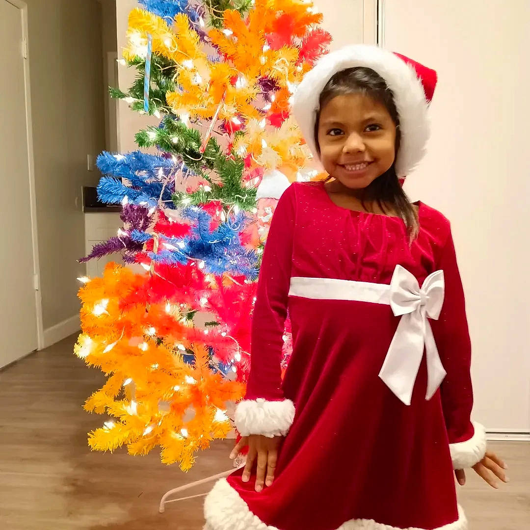 Jayde is registered to the contest to win money with this photo: christmas, christmas_decoration, christmas_ornament, christmas_tree, event, fashion_design, fun, happy, hat, holiday, holiday_ornament, joy, ornament, person, plant, red, sleeve, smile, standing, tradition