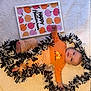 baby, infant, halloween, orange_clothing, striped_pants, blanket, garland, ghosts, pumpkins, sign, holiday, festive, cute, lying_down, indoors, decorations, child, celebration, smiling, portrait