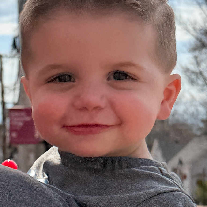 Jaxson joined the competition — help win amazing prizes! child, toddler, smile, face, haircut, outdoor, blue_sky, tree, clothing, nike_logo, person, portrait, daylight, happy, cute, holding, head, shoulder, casual_wear, background