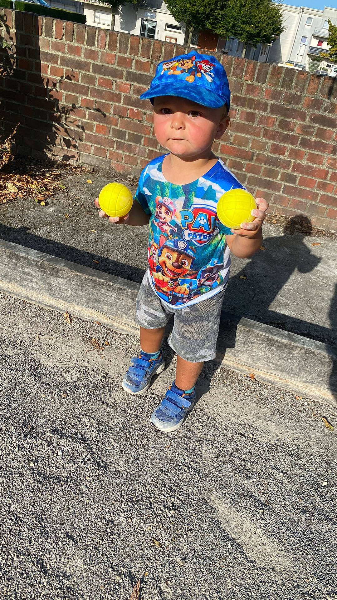 John participe au concours pour gagner de l'argent avec cette photo : asphalt, baby_toddler_clothing, balloon, baseball_cap, cap, child, electric_blue, happy, headwear, leisure, person, personal_protective_equipment, road, road_surface, shorts, sidewalk, sleeve, sneakers, standing, t_shirt