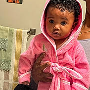 Kehlani is registered to the contest to win money with this photo: baby, child, person, pink_robe, curly_hair, hood, bathroom, towel, hand, earring, portrait, indoor, cute, expression, adult_hand, wall_art, mirror, skin, clothing, young