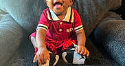 Kehlani is registered to the contest to win money with this photo: baby, child, smiling, red_dress, bow, shoes, armchair, happy, tongue_out, cute, indoor, portrait, person, sitting, infant, black_hair, clothing, playful, young_child, cozy