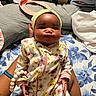 Kehlani joined the competition — help win amazing prizes! baby, infant, child, floral_onesie, headband, pouty_face, person, hand, lap, bedspread, blue_flower_pattern, pacifier, bracelet, indoor, skin, cute, young_child, sitting, cozy, family
