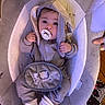 baby, pacifier, hood, baby_seat, gray_clothing, socks, plush, infant, cute, child, indoor, fabric, pouch, hand, floor, pattern, toy, soft, seated, curious