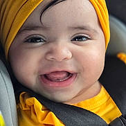 Allison is registered to the contest to win money with this photo: baby, child, smiling, yellow_turban, yellow_clothing, car_seat, safety_belt, closeup, face, cute, happy, infant, portrait, indoors, person, seatbelt, headwear, bright_colors, cheerful, small_child