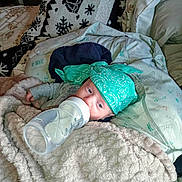 Maverick is registered to the contest to win money with this photo: baby, bottle, blanket, bandana, bed, bedding, comfort, cozy, feeding, infant, milk, person, portrait, sleepwear, soft, toddler, toy, warm, young, indoors