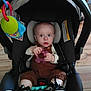 Maverick joined the competition — help win amazing prizes! baby, car_seat, toy, infant, sneakers, brown_overalls, indoor, child, flooring, plastic_toy, seatbelt, wide_eyes, holding, footwear, person, cute, small_hands, head_support, colorful, childcare