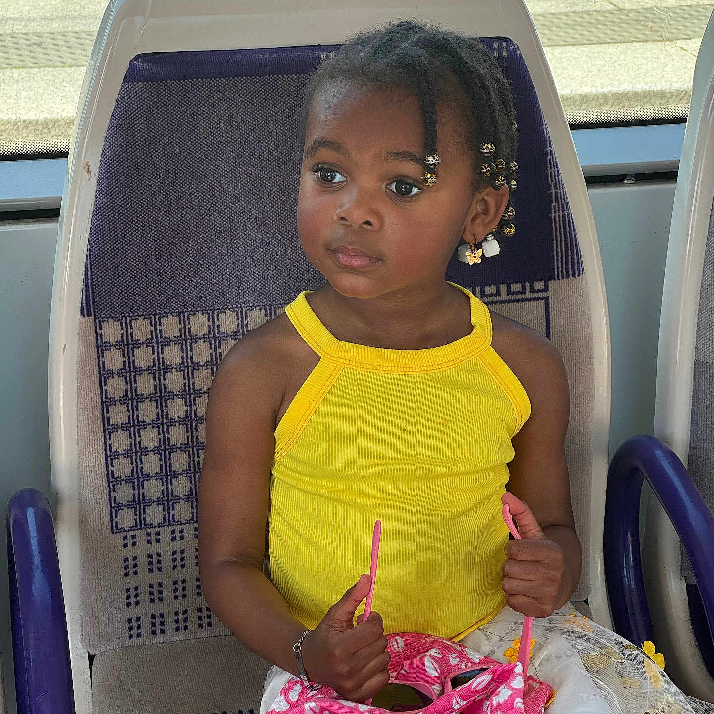 Laysha participe au concours pour gagner de l'argent avec cette photo : beads, braided_hair, bus_seat, casual, child, clothing, curious, daylight, earrings, girl, hands, patterned_fabric, person, pink_bag, portrait, public_transport, sitting, window, yellow_tank_top, young