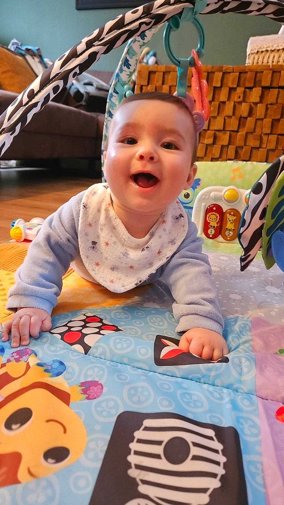 Mylann a rejoint le concours — aidez-le/la à gagner de superbes lots ! baby, bib, child, clothing, colorful, crawling, cute, floor, furniture, hand, happy, head, indoor, living_room, person, play_mat, smiling, soft_toys, toy, young_child