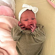 Giulia a rejoint le concours — aidez-le/la à gagner de superbes lots ! baby, newborn, headband, bow, infant, clothing, blanket, soft, cute, lying_down, hand, face, indoors, cozy, pink, beige, person, sleepwear, portrait, resting