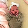 baby, newborn, headband, bow, infant, clothing, blanket, soft, cute, lying_down, hand, face, indoors, cozy, pink, beige, person, sleepwear, portrait, resting