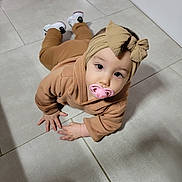Catalyna a rejoint le concours — aidez-le/la à gagner de superbes lots ! baby, bow, brown_clothing, child, closeup, crawling, cute, expression, floor, footwear, hand, headband, indoors, infant, looking_up, pacifier, person, shoes, tile, young_child