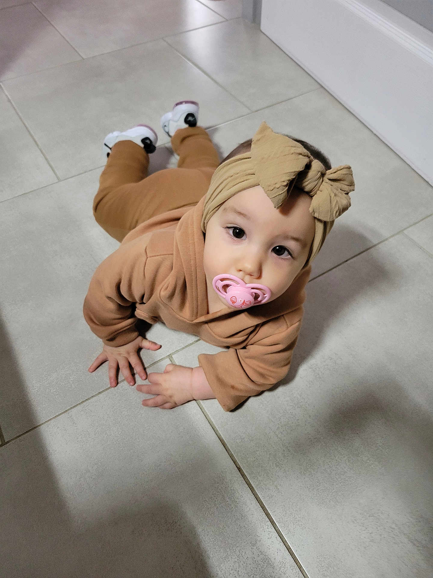 Catalyna a rejoint le concours — aidez-le/la à gagner de superbes lots ! baby, bow, brown_clothing, child, closeup, crawling, cute, expression, floor, footwear, hand, headband, indoors, infant, looking_up, pacifier, person, shoes, tile, young_child