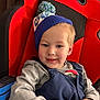 Bentlee joined the competition — help win amazing prizes! beanie, blonde_hair, car_seat, casual_clothing, cheeks, child, cozy, eyes, fabric_texture, gray_shirt, hands, happy, indoor, overalls, pompom, portrait, red_seat, smile, toddler, toy_cube