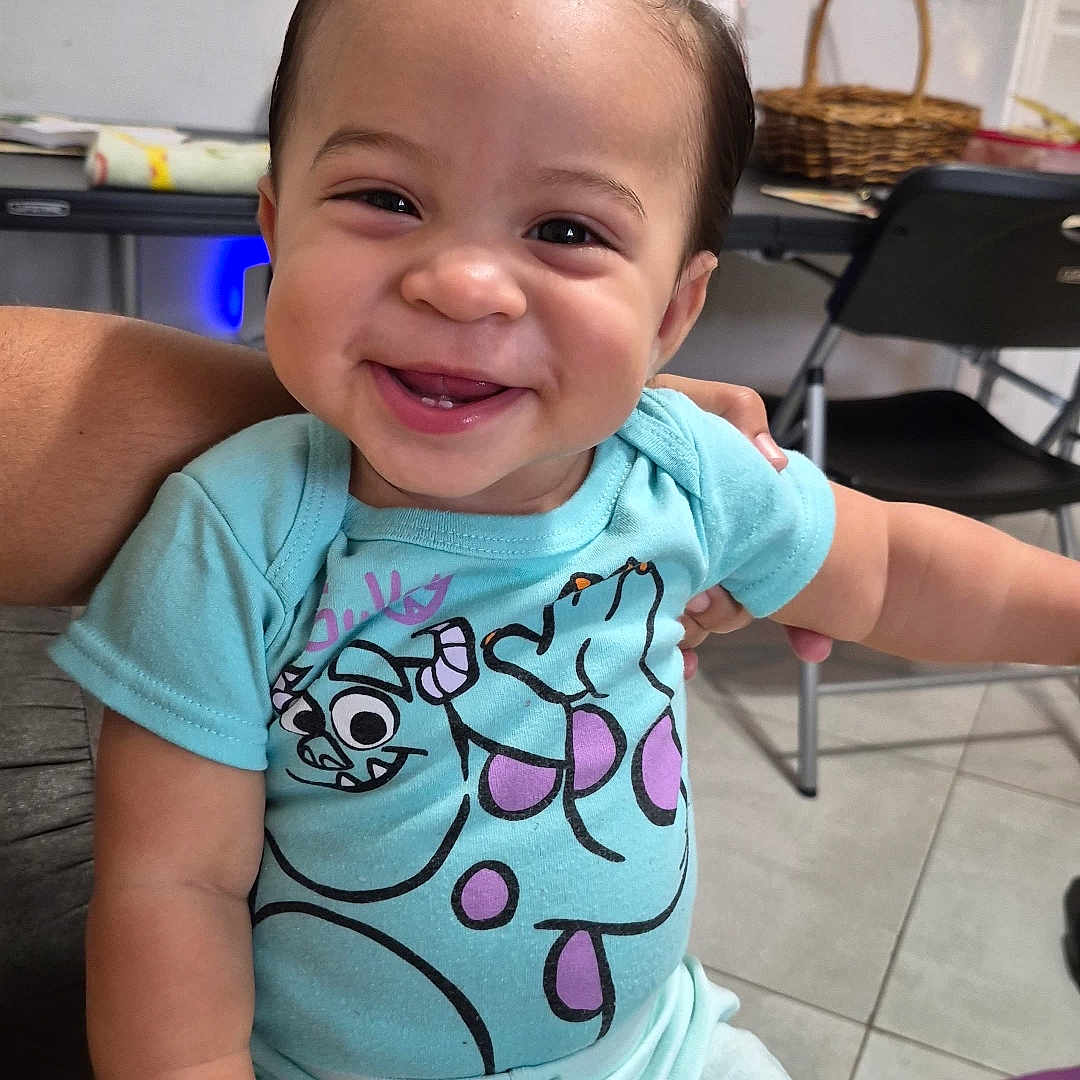 Dariel joined the competition — help win amazing prizes! baby, child, smiling, happy, indoor, person, clothing, blue_shirt, sitting, floor, toy_mat, arm, furniture, basket, chair, face, cute, portrait, toddler, hair