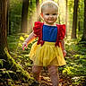 child, toddler, girl, portrait, smiling, forest, outdoors, sunlight, sunbeams, trees, nature, dress, costume, colorful_clothing, red, blue, yellow, walking, foliage, fairytale
