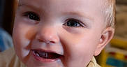 Stevie joined the competition — help win amazing prizes! baby, background, child, closeup, clothing, cute, expression, eyes, face, happy, head, indoors, infant, person, portrait, shirt, skin, smile, teeth, young