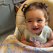 Layna participe au concours pour gagner de l'argent avec cette photo : toddler, high_chair, messy, food, spoon, smiling, curly_hair, kitchen, baby, face_paint, happy, colorful, child, feeding, playful, cute, indoor, bib, table, expression