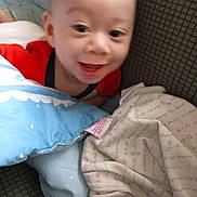 Astor is registered to the contest to win money with this photo: baby, smiling, pillow, blanket, infant, face, couch, clothing, happy, indoor, child, closeup, cute, soft, cozy, person, portrait, head, toddler, fabric