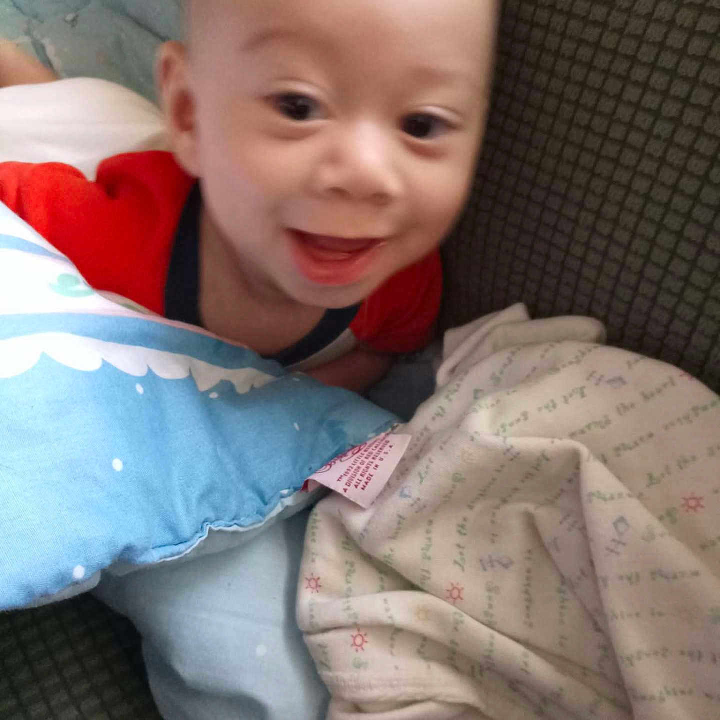 Astor is registered to the contest to win money with this photo: baby, smiling, pillow, blanket, infant, face, couch, clothing, happy, indoor, child, closeup, cute, soft, cozy, person, portrait, head, toddler, fabric