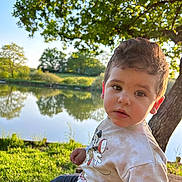 Zakaria a rejoint le concours — aidez-le/la à gagner de superbes lots ! toddler, child, outdoor, pond, tree, grass, sunlight, mickey_mouse, sweatshirt, pants, shoes, nature, reflection, portrait, young_child, casual_clothing, daytime, curious, cute, park