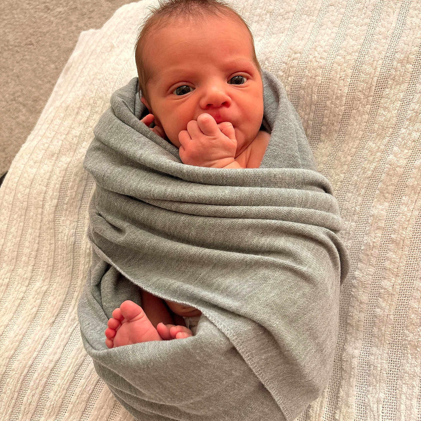 Elliana is registered to the contest to win money with this photo: newborn, baby, infant, child, portrait, swaddled, blanket, gray_blanket, baby_feet, tiny_hands, fist, hand_to_mouth, wide_eyed, lying_down, cozy, indoor, bed, textile, closeup, cute