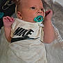 baby, pacifier, infant, onesie, nike, hand, blanket, clothing, person, newborn, cute, sleepwear, soft, resting, indoors, small, child, face, skin, young