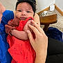 Amani joined the competition — help win amazing prizes! baby, child, headband, red_dress, holding, indoor, carpet, wooden_chair, curious_expression, person, hand, face, clothing, seated, closeup, young_child, human, skin, arm, fingers